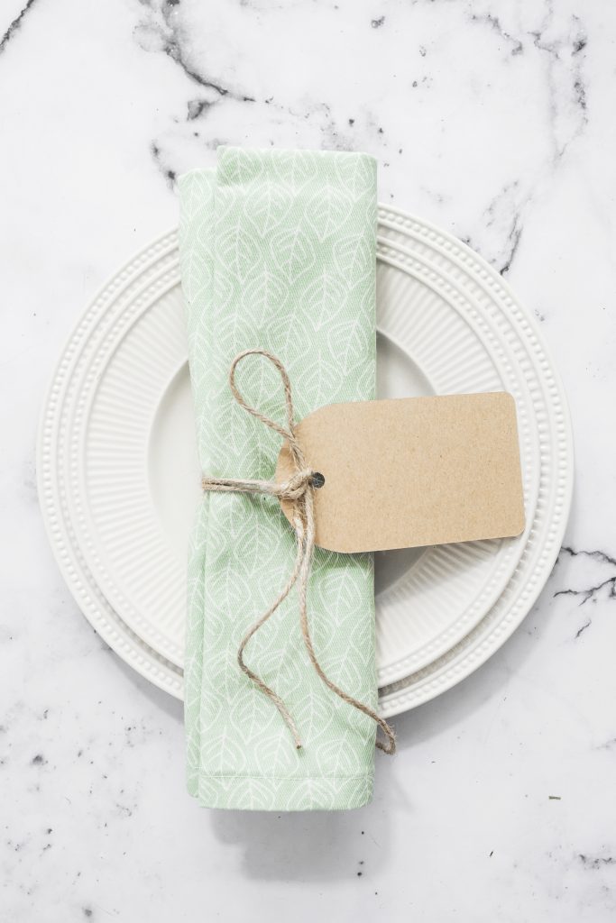 Folded napkin tied with blank tag on an empty flat round plate