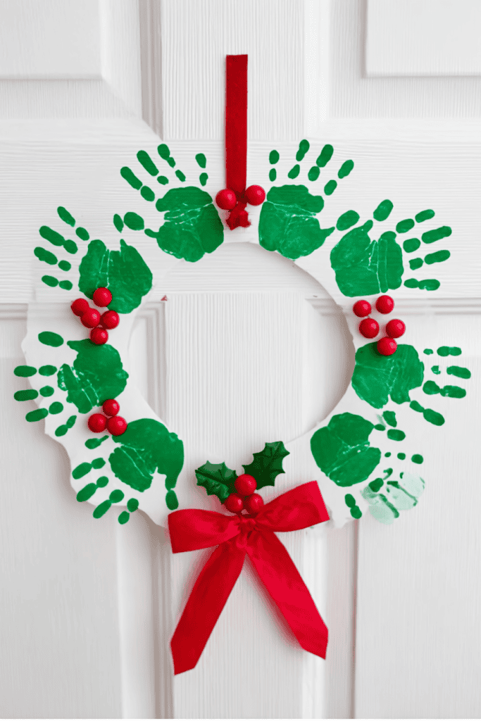DIY handprint wreath craft, green paper handprints cut and layered in a circle to form a wreath