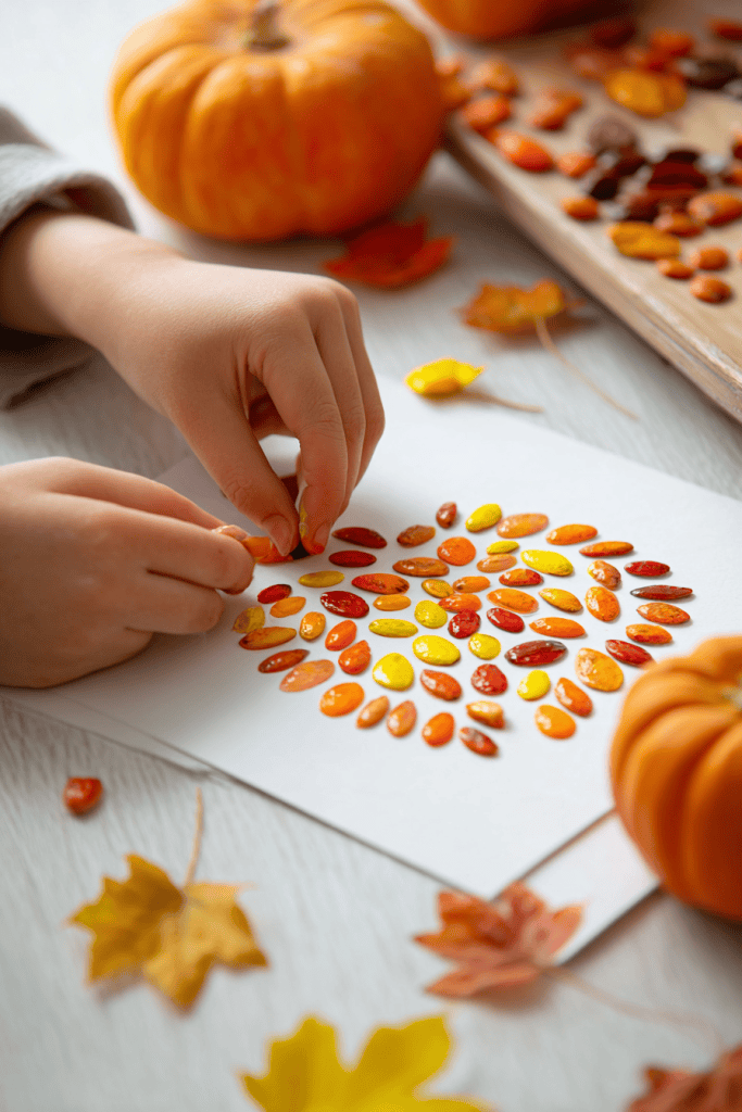 Child’s hands making pumpkin seed art