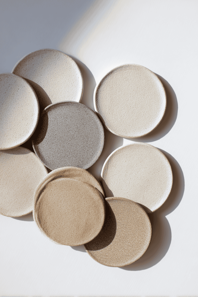 Set of handmade round clay coasters, smooth matte finish, light neutral tones (ivory, pale gray, soft beige)