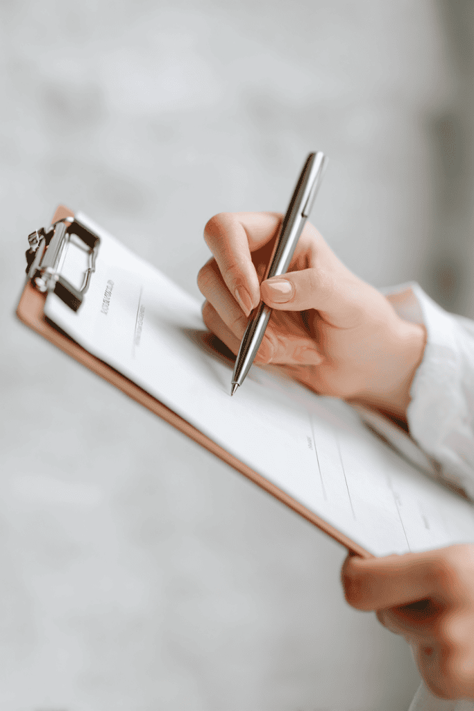 Expecting mom’s hand holding pen, writing preferences on a natural birthing plan checklist, paper on clipboard
