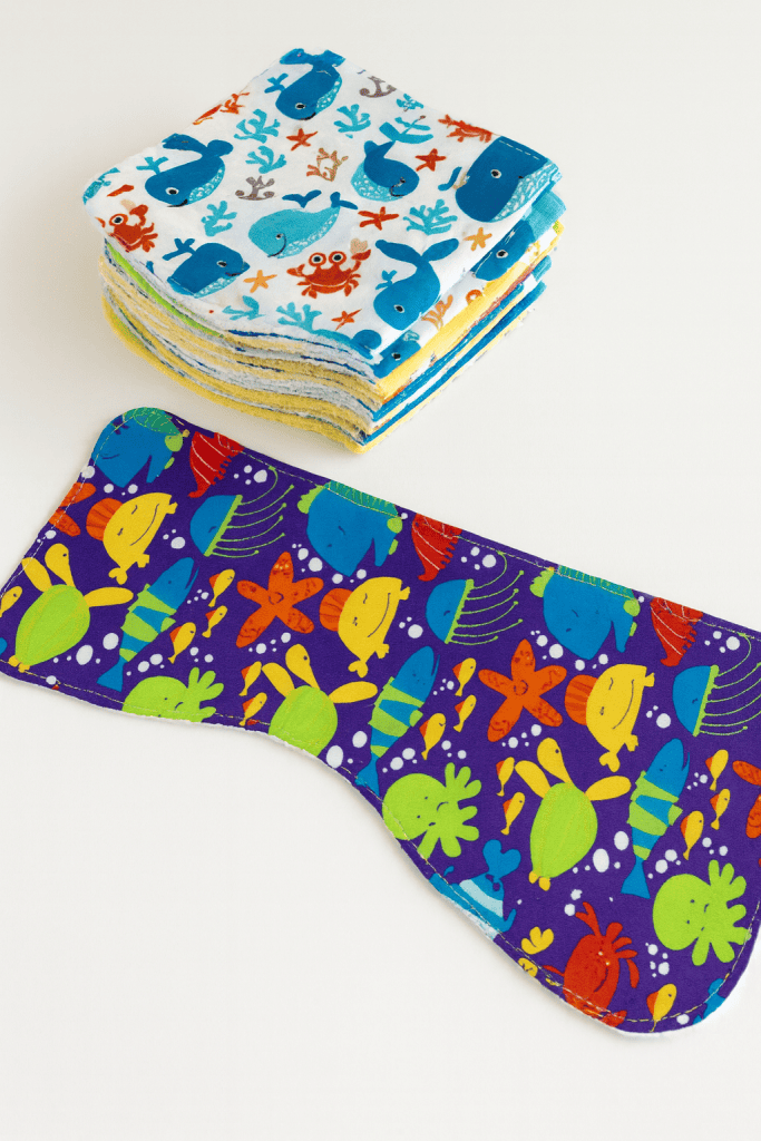 a colorful set of handmade baby burp cloths arranged neatly on a smooth white surface