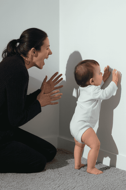 a mother and her baby interacting with hand shadows on a clean white wall