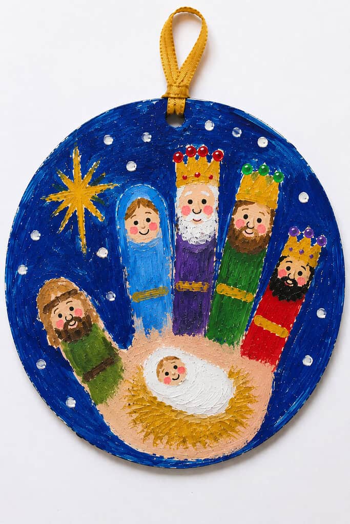 A round handprint nativity ornament with baby Jesus in the palm as a manger and the fingers painted as Mary, Joseph, and the three kings.