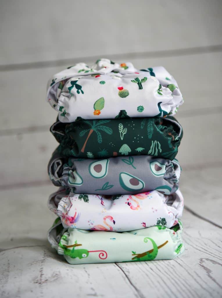 A vertical stack of five cloth diapers placed on a white wooden floor.