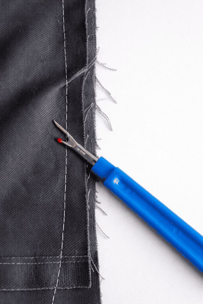 Frayed fabric and seam ripper close-up
