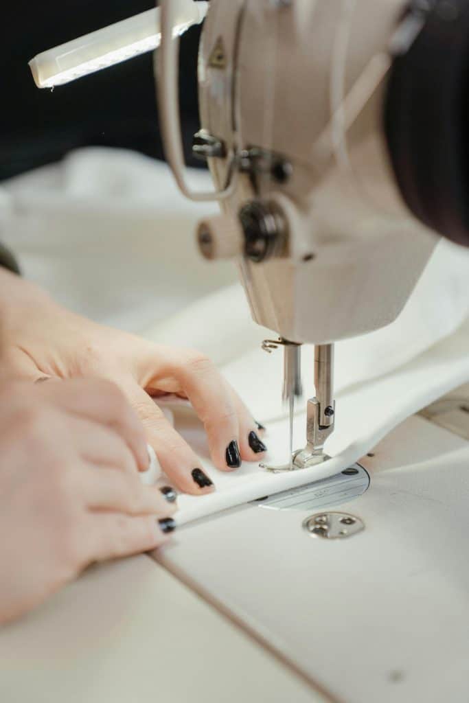 a person using a sewing a white sewing machine