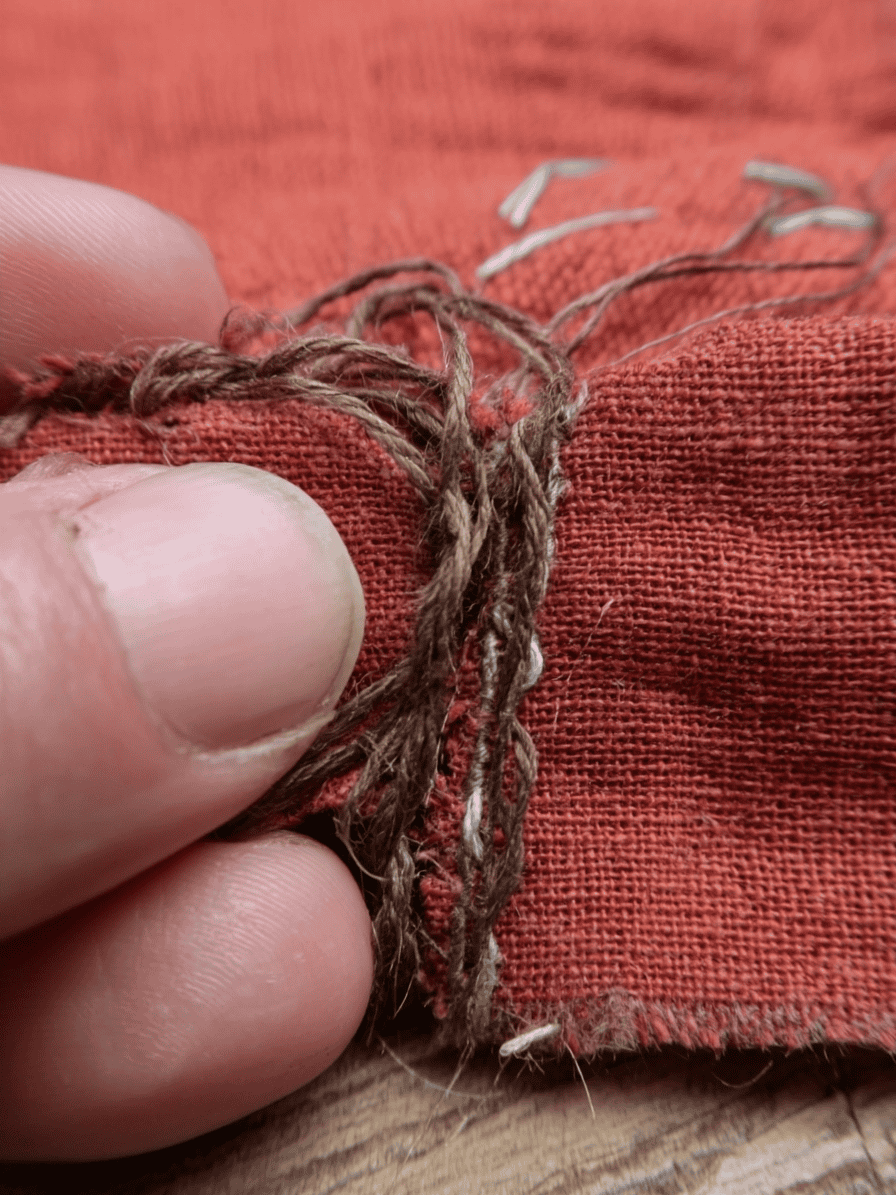 sewing thread bunching up underneath a piece of rust-red fabric