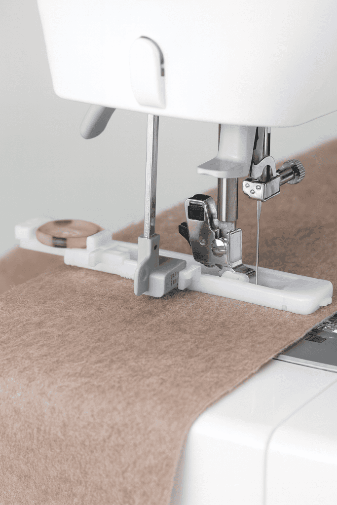 close-up of a sewing machine with buttonhole foot attachment sewing beige fabric