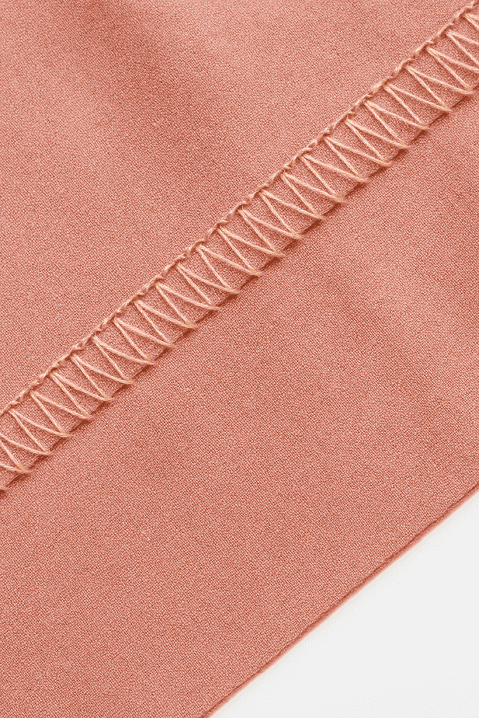 Close-up of fabric with a flatlock stitch, showing the ladder-like seams joining two fabric edges smoothly and evenly.