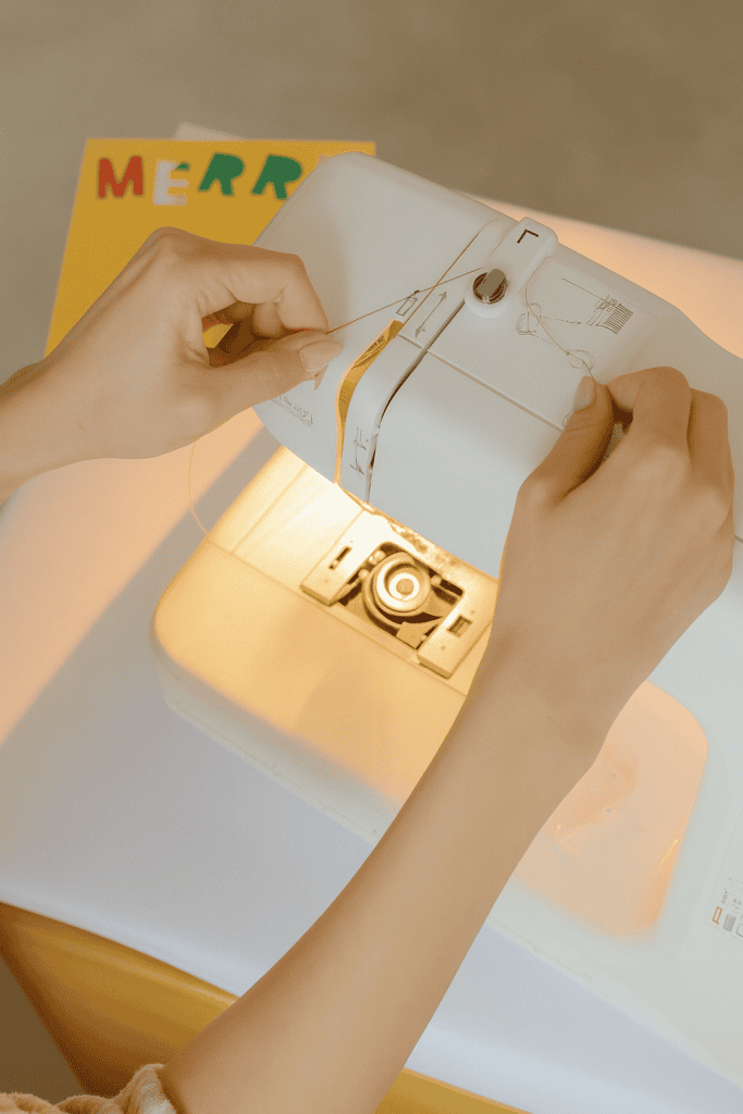a person threading a modern white sewing machine