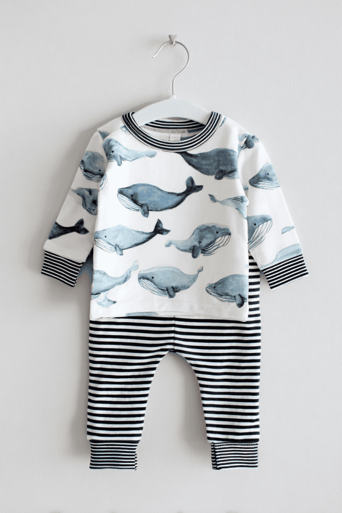 a baby outfit displayed on a white plastic hanger against a clean, white wall