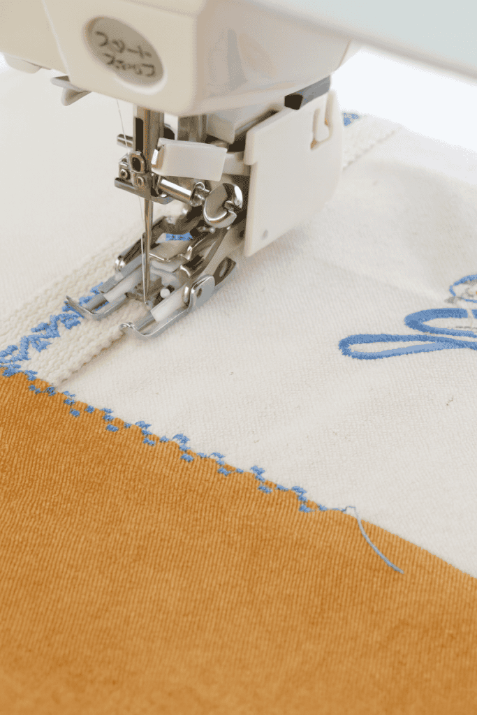 close-up of a sewing machine with walking foot (even feed foot) stitching layered fabric with embroidery