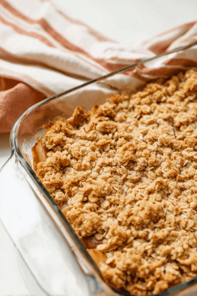 a freshly baked apple crisp with golden oat topping in a square glass baking dish