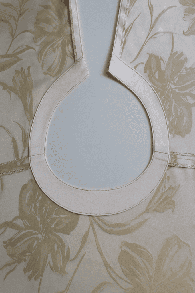 close-up of a sewing project showing neckline facing attached to floral fabric garment, viewed from the inside