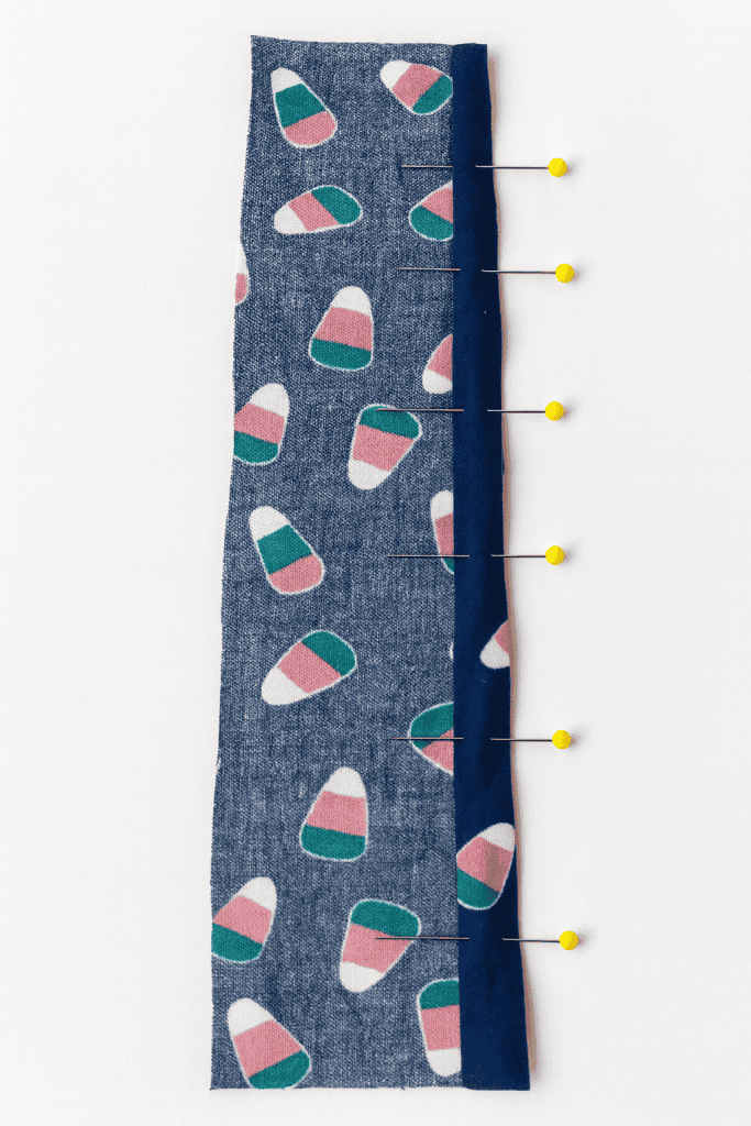 close-up top-down photograph of two strips of fabric pinned together along one edge, ready for sewing