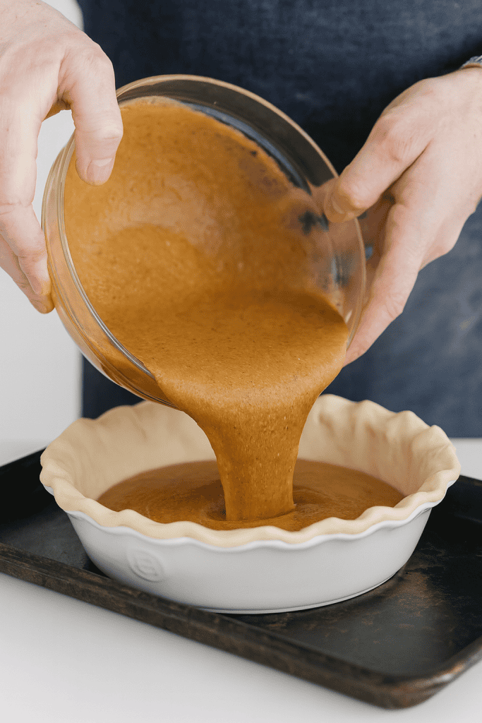 a baker pouring freshly mixed Shoofly Pie filling into an unbaked pie crust
