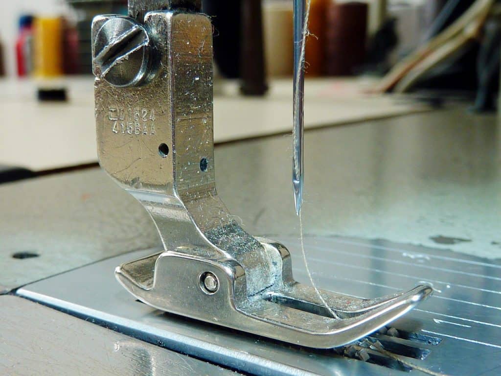 close-up of a sewing machine presser foot and needle with a thread