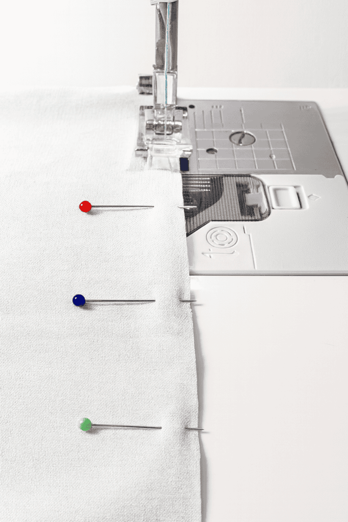 a sewing machine in the process of stitching two layers of light-colored fabric.