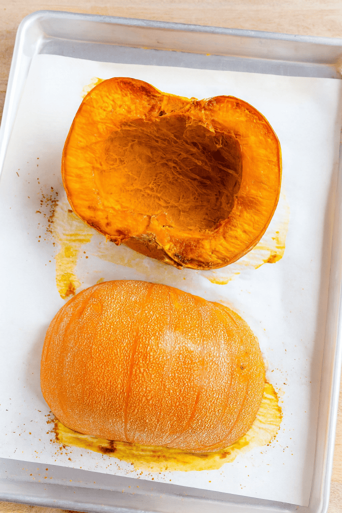 a freshly roasted sugar pumpkin, sliced in half and placed on a parchment-lined baking tray