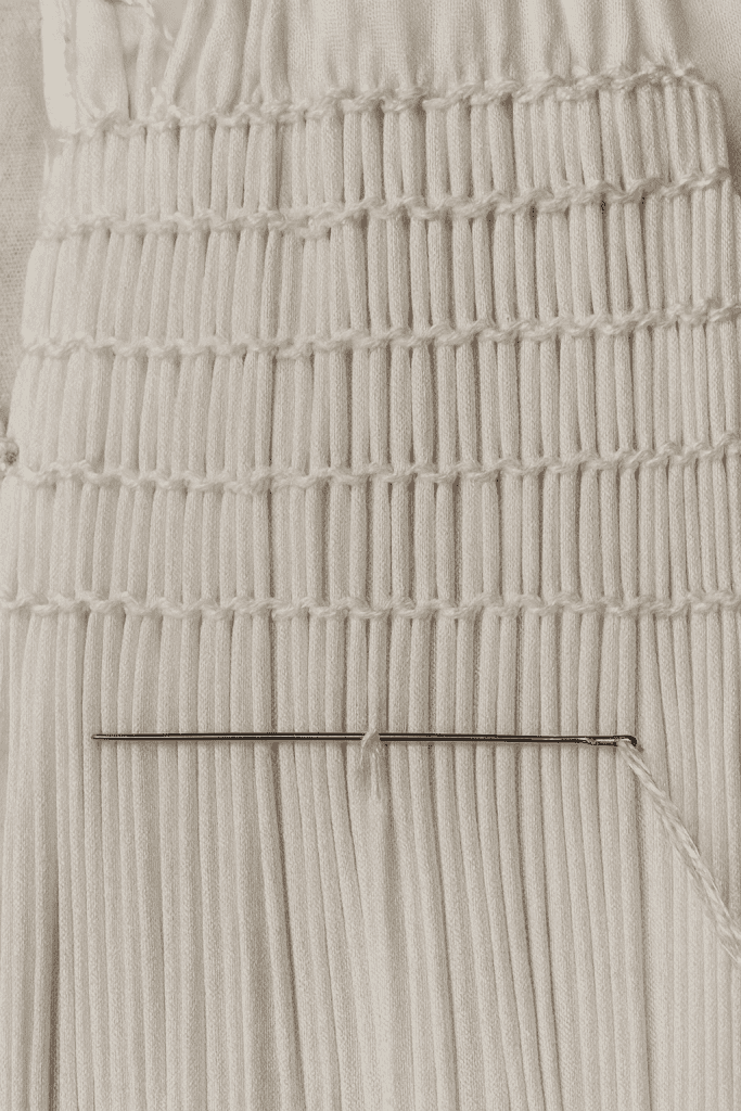 a white fabric undergoing hand-smocking