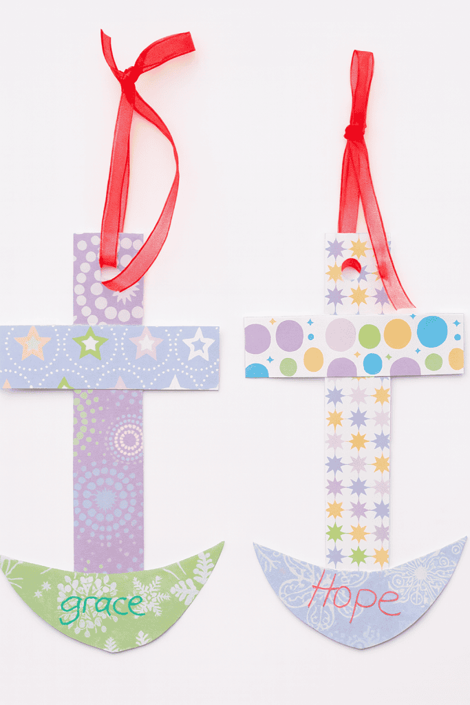 two handcrafted paper anchor-cross decorations hanging from a horizontal string.