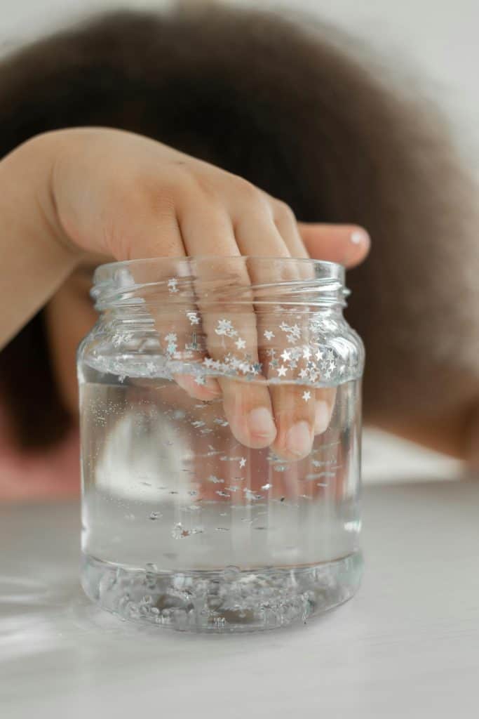 Girl putting hand in jar with water