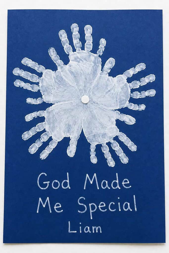 a handmade snowflake craft made of white painted handprints on blue cardstock with the words God Made Me Special written beneath it