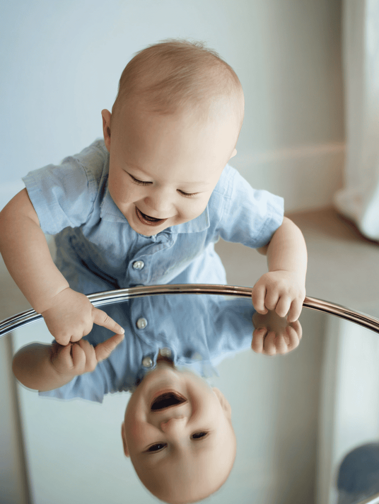 a baby interacting joyfully with their reflection in a round mirror tabletop