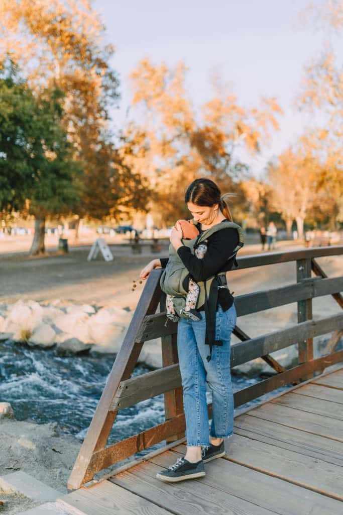 A Woman Standing on a Wooden Bridge with Her Baby