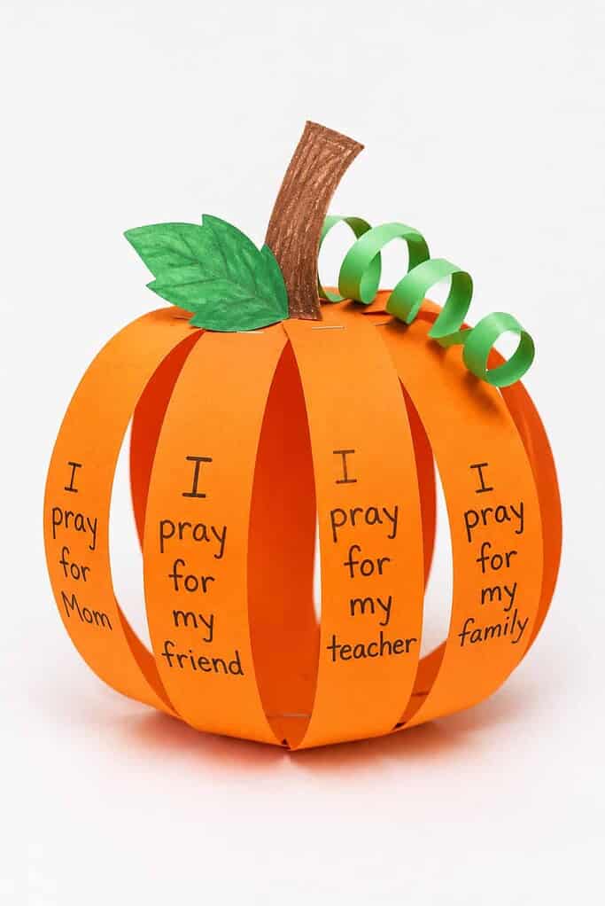 a handmade 3D pumpkin craft made of orange paper strips with handwritten prayers on each strip and a curly green paper stem