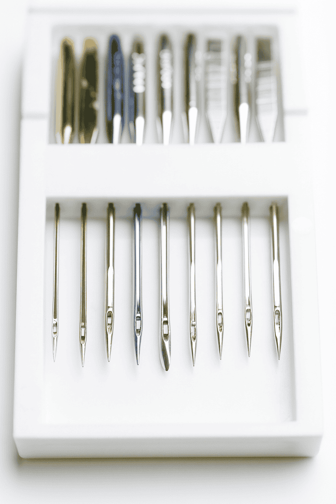 a neatly arranged set of sewing machine needles in a white plastic case