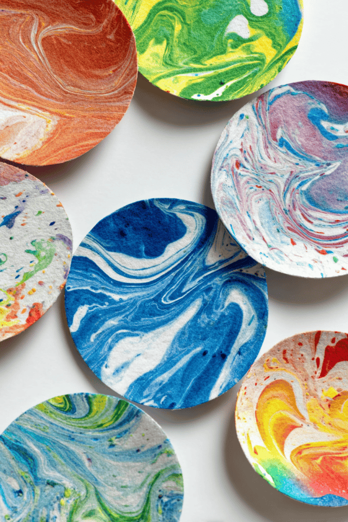 several hand-cut circular pieces of paper with vibrant, marbled paint patterns