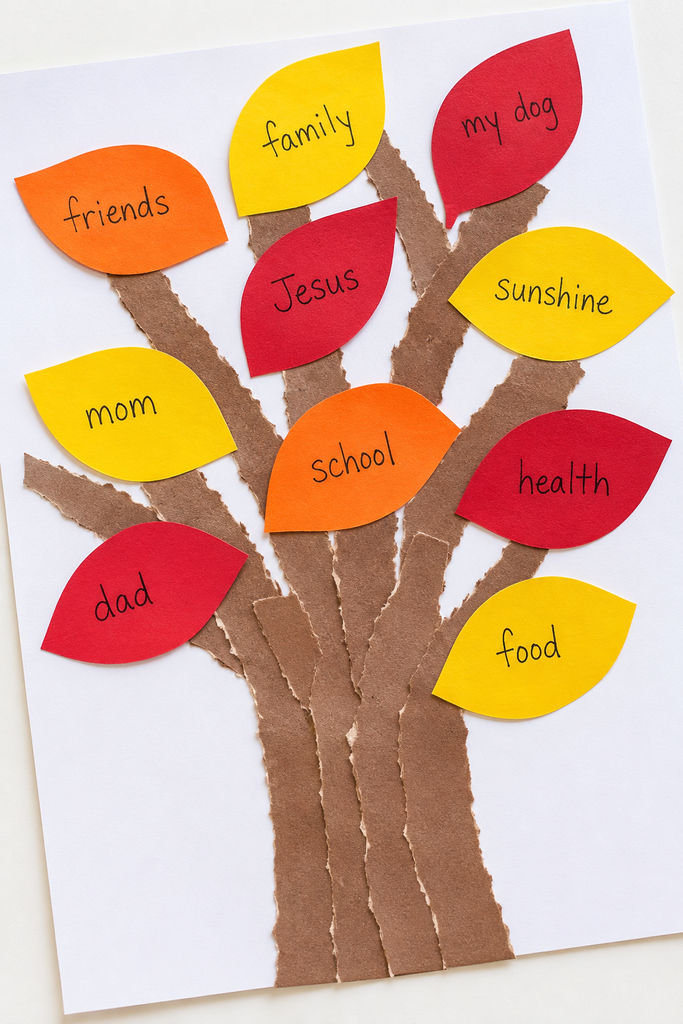 a handmade thankful tree craft with a torn brown paper trunk and red, orange, and yellow paper leaves with handwritten words on them