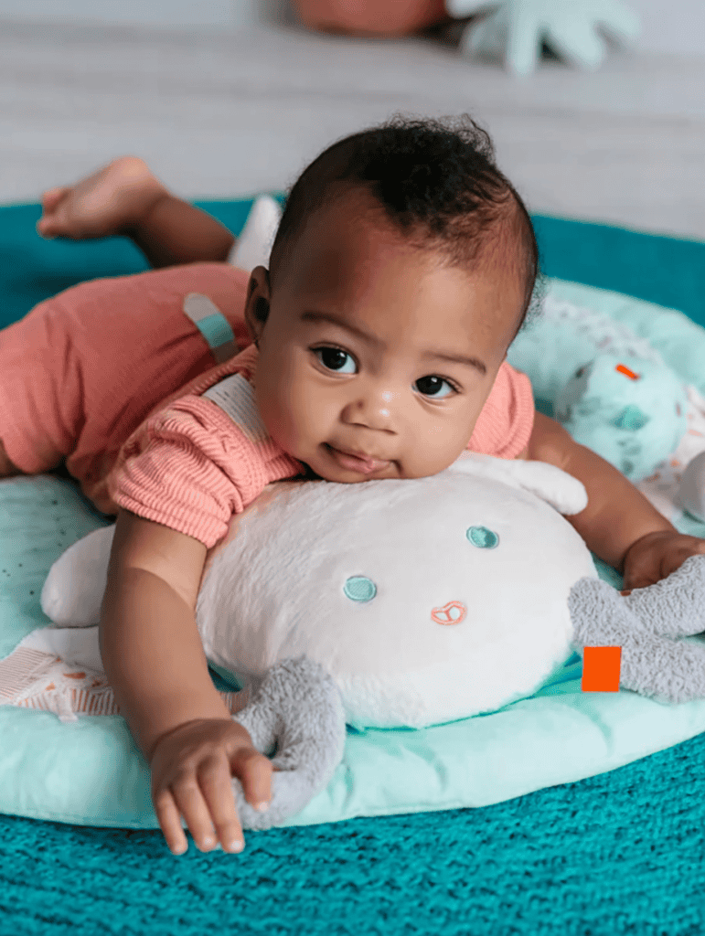 a baby during tummy time, resting on a soft, colorful play mat designed for developmental support