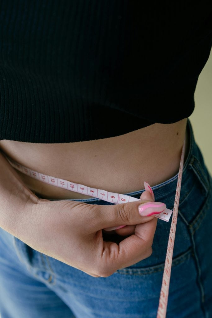 a woman measuring her waist