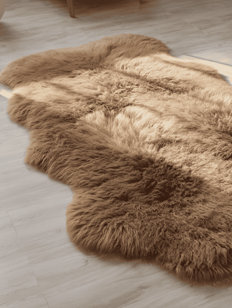 a luxurious, oversized brown sheepskin rug laid out across a smooth, light-colored wooden floor