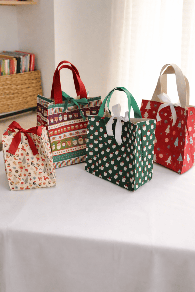 four festive handmade Christmas gift bags made from fabric