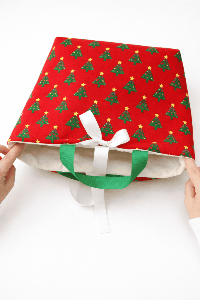 a handmade holiday-themed tote bag being gently opened by a pair of hands