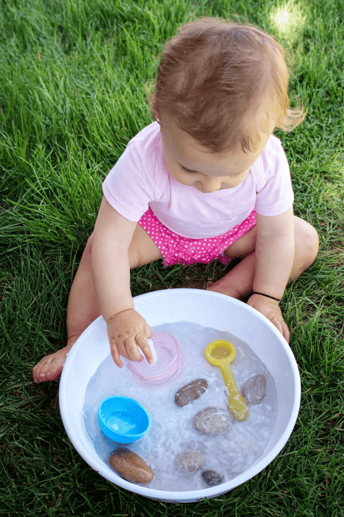 a baby engaging in a sensory water play activity outdoors