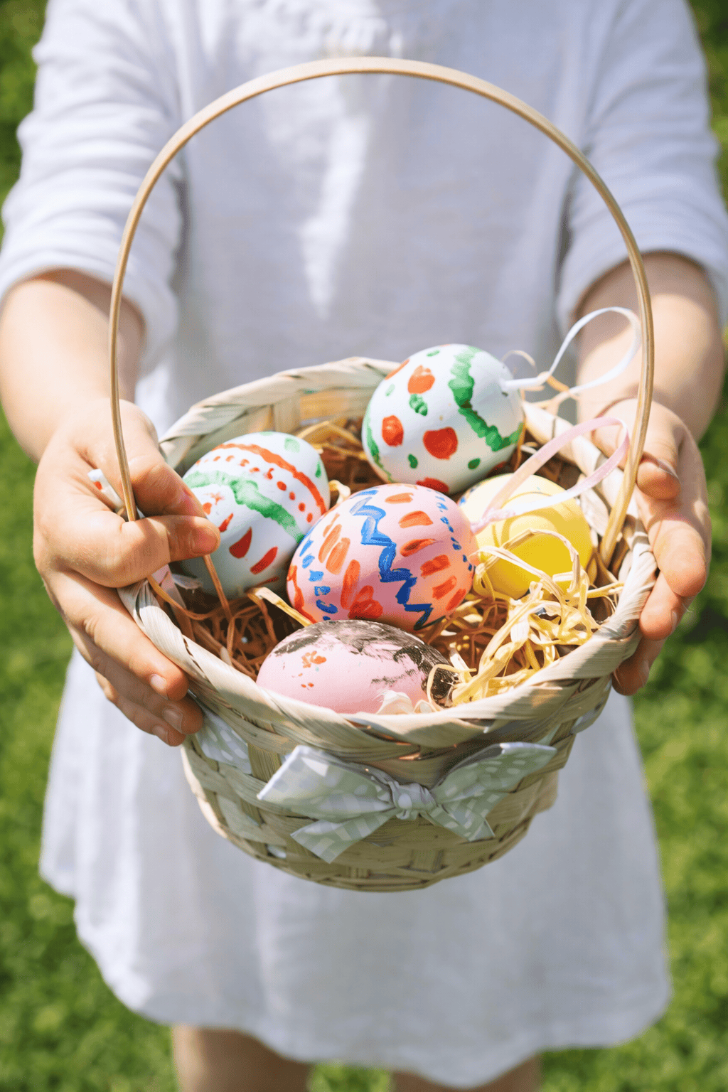 a young child holding an Easter basket filled with hand-painted Easter eggs.