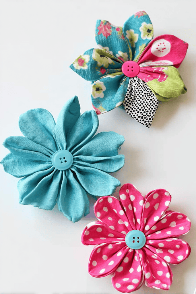 three handmade fabric flowers made from colorful fabric scraps,