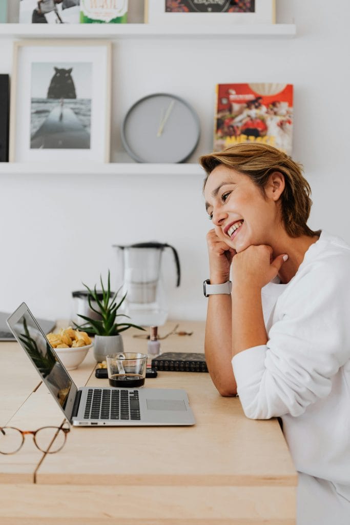 a cheerful young woman engaging in a video call on her laptop