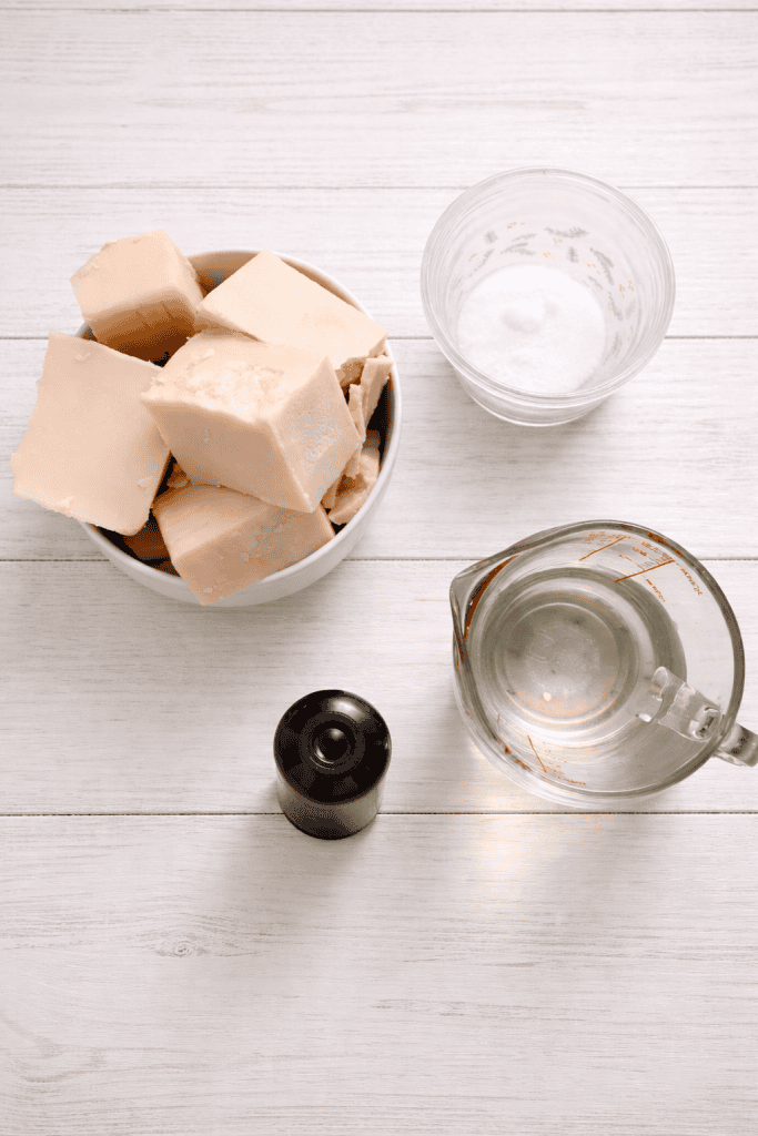 natural soap-making ingredients neatly arranged on a clean white wooden surface.