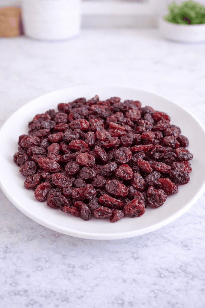 a heaping pile of dried cranberries arranged on a clean, white ceramic plate