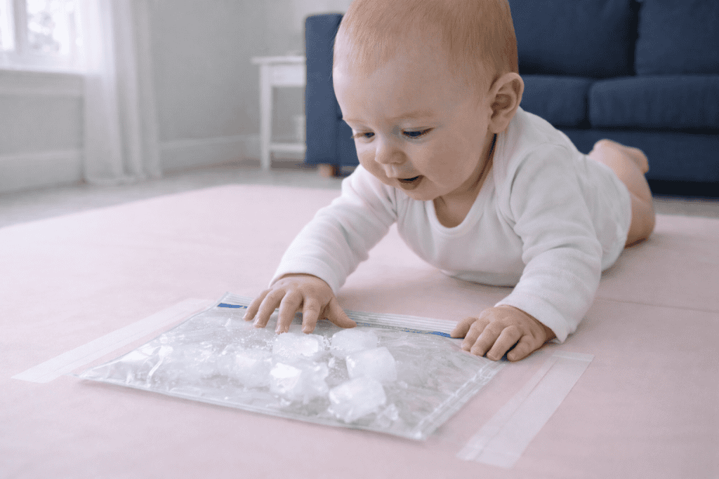 Curious baby explores ice cubes during tummy time