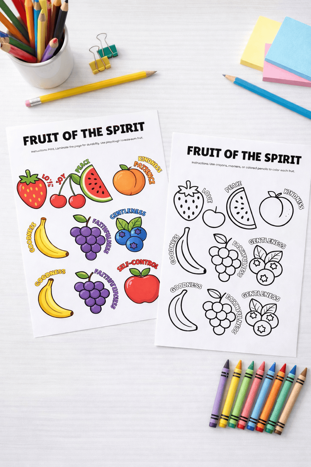 two children’s printable activity sheets titled “FRUIT OF THE SPIRIT” placed on a clean white desk