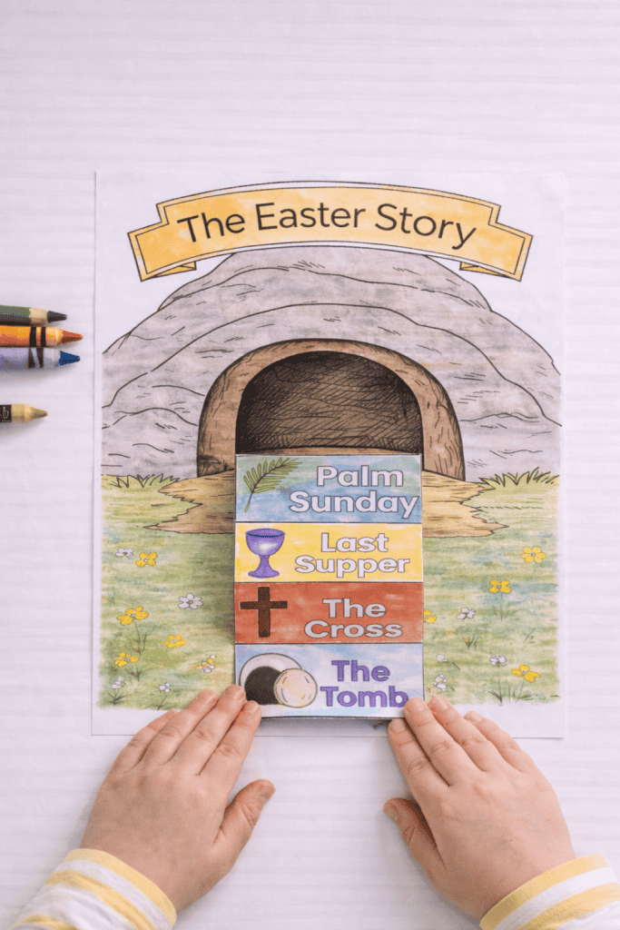 Top-down view of a printed “The Easter Story” tomb page on a white table with the folded story strip glued below the tomb entrance