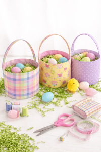 three pastel-colored Easter baskets arranged on a white wooden surface