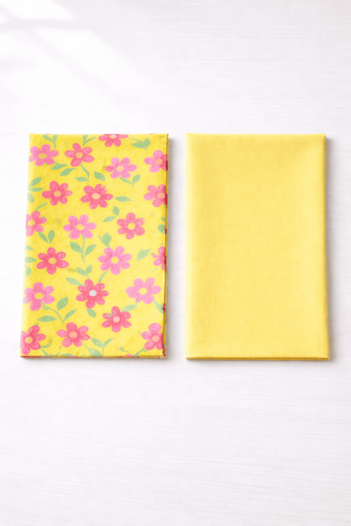 two neatly folded fabric pieces displayed side by side on a smooth, light neutral surface.